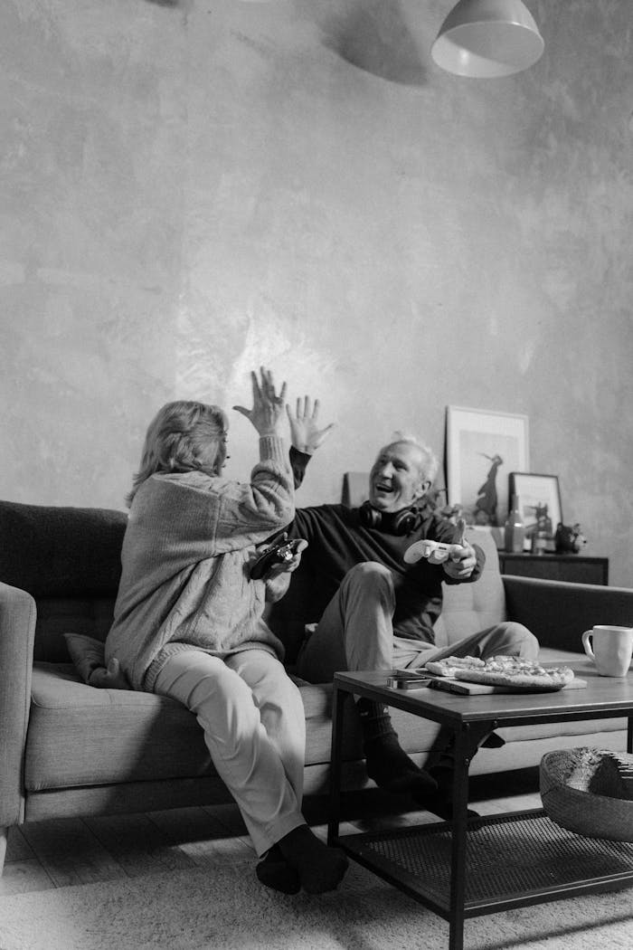 Senior couple enjoying video games together on the sofa at home, having fun.